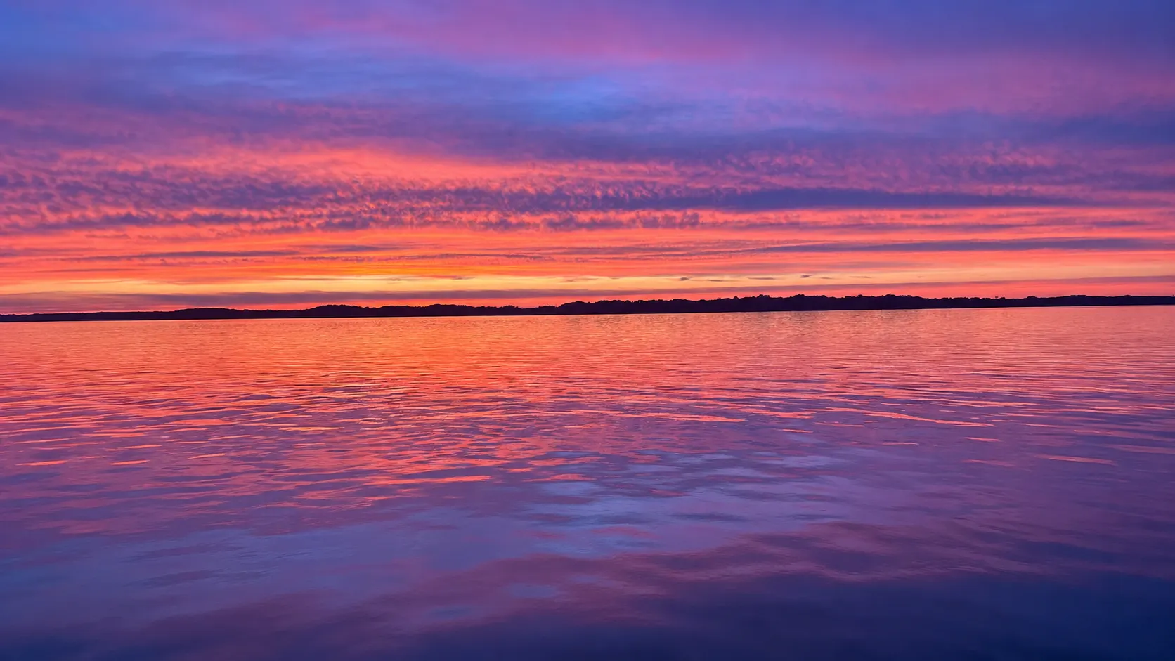 Golden sunset over the St. Lawrence River seen from the deck rail of a sightseeing boat