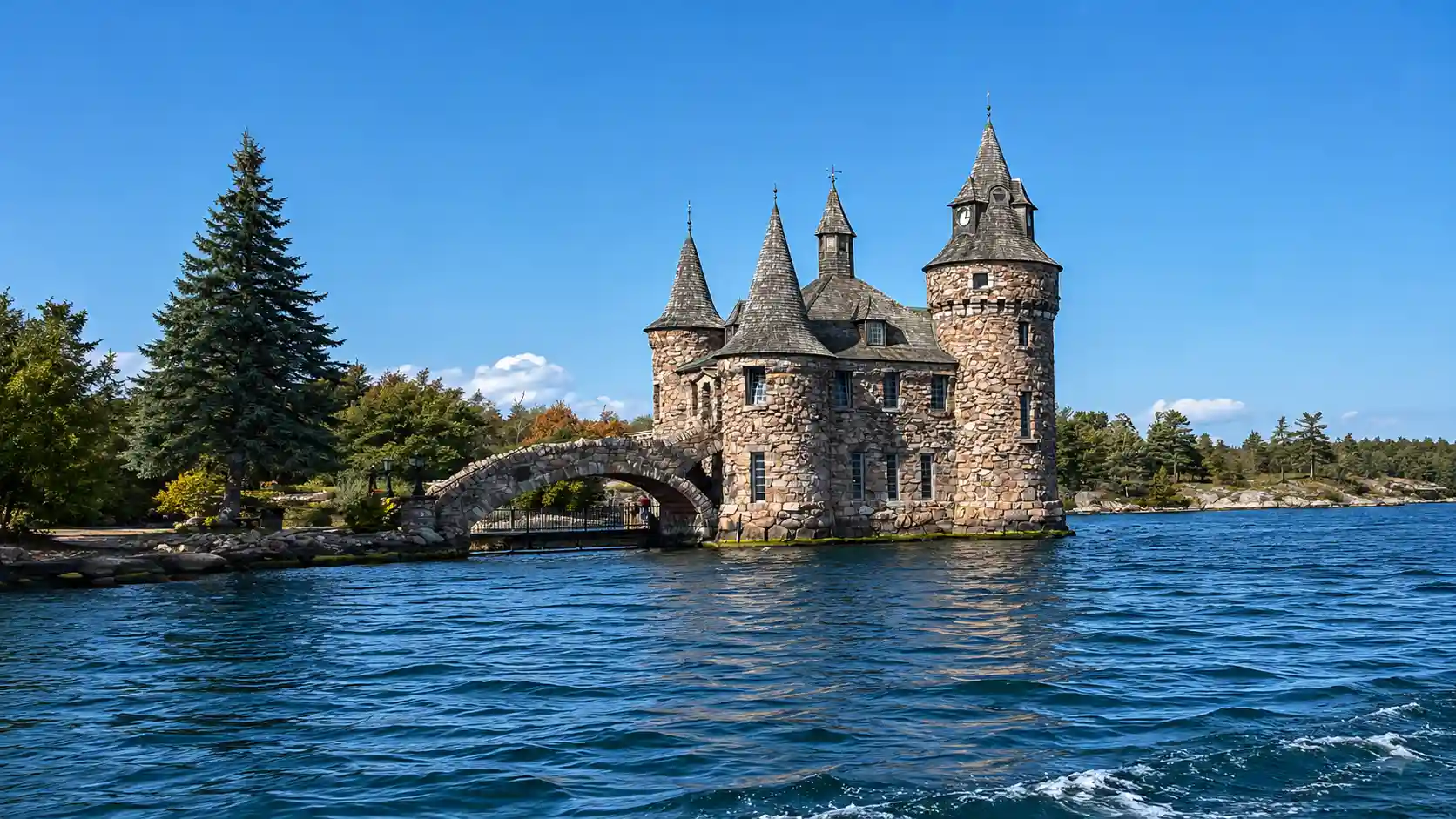Stone castle with turrets rising from a small island on a calm blue river