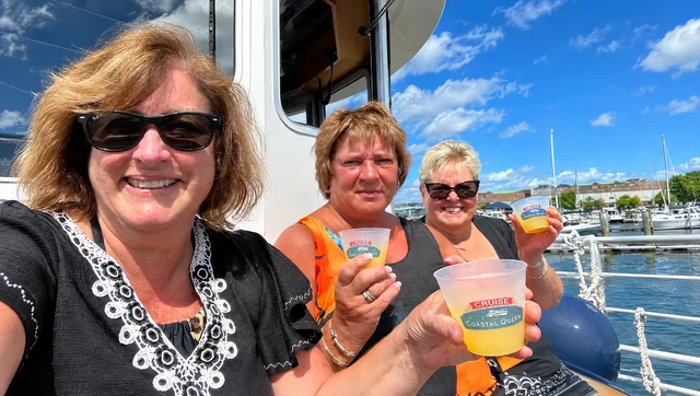 Passengers enjoying drinks aboard a sightseeing boat at a waterfront marina