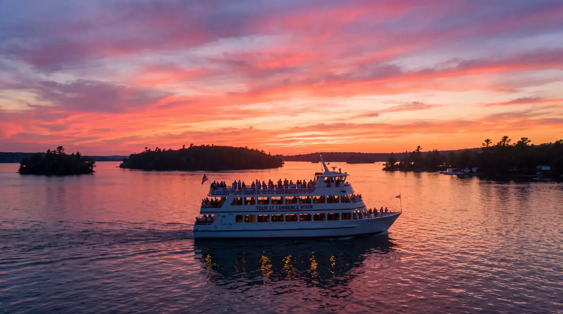 Golden sunset over the St. Lawrence River seen from the deck rail of a sightseeing boat