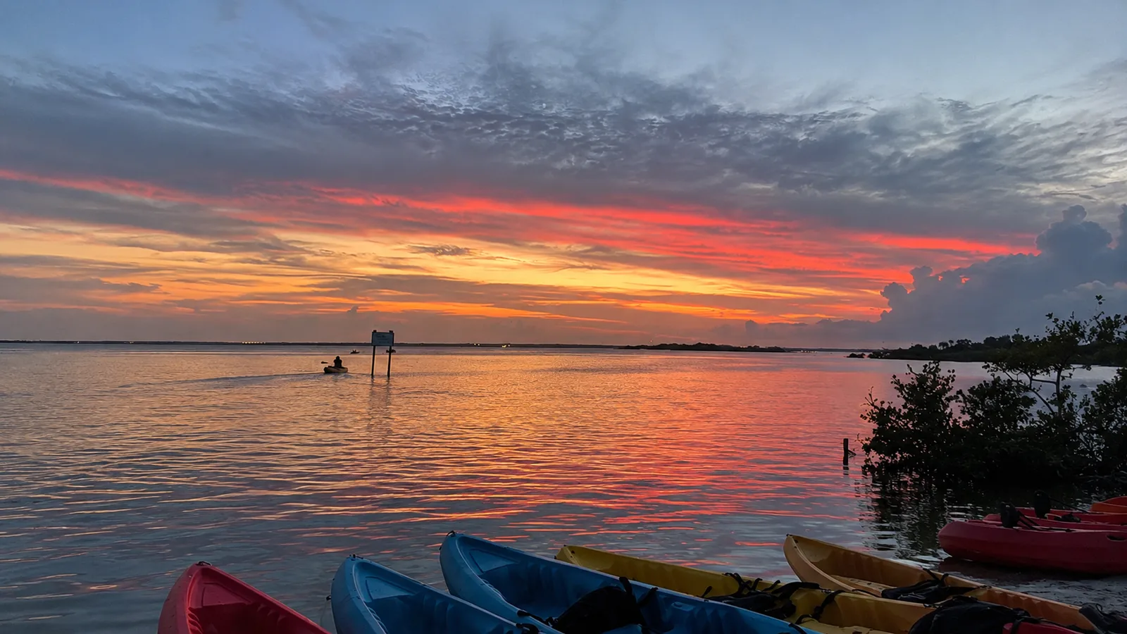 Sunset sky over calm water with kayaks pulled up on the shore in Cocoa Beach, Florida