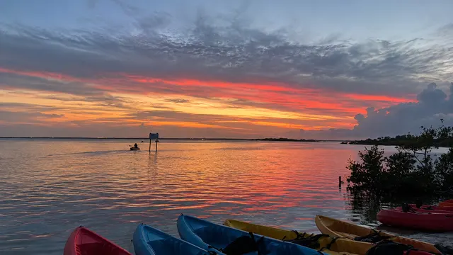 Sunset sky over calm water with kayaks pulled up on the shore in Cocoa Beach, Florida